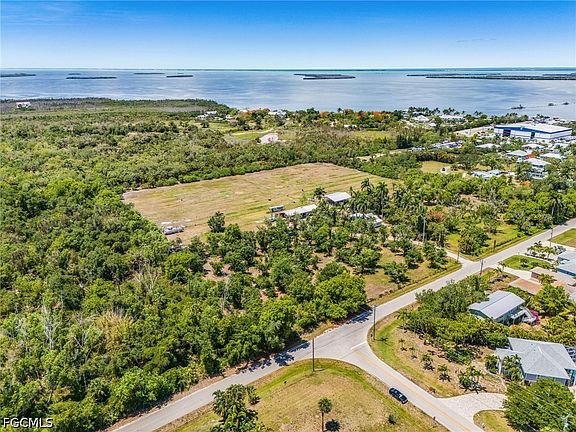 High aerial of the 9.5-acre parcel cleared into paddocks, with Pine Island Sound and barrier islands stretching across the entire horizon line