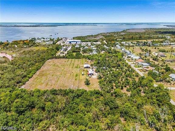 Wide aerial of the rectangular cleared parcel with the working neighborhood of Pineland and the bay all visible in one frame