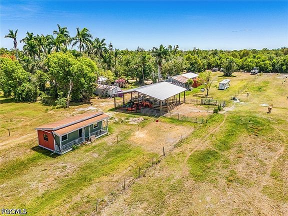 Close aerial of the established stables, working outbuildings, fenced paddocks, and the small cottage along the eastern boundary of the parcel